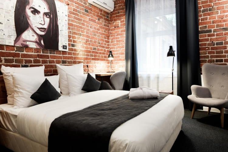 WineWood room 208 Standard with a bed against an exposed brick wall and a courtyard window